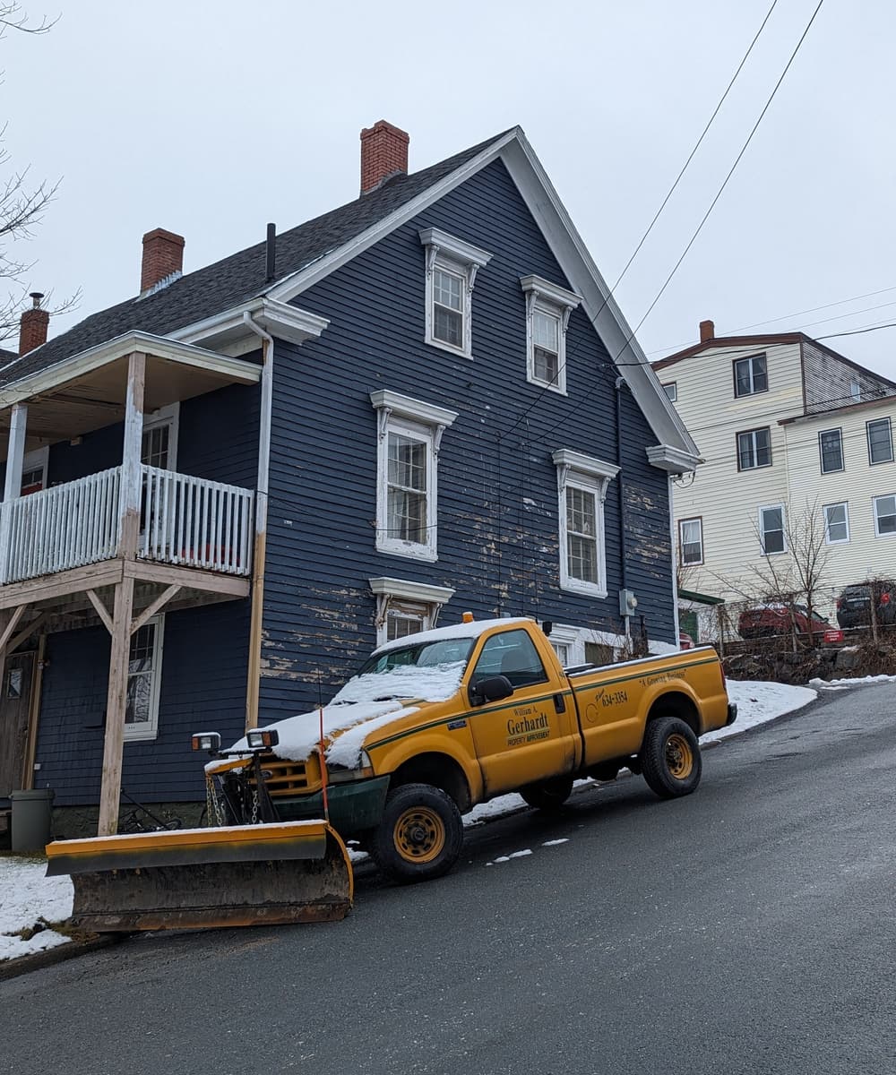 A pickup truck fitted with a snow plow blade on a winter street
