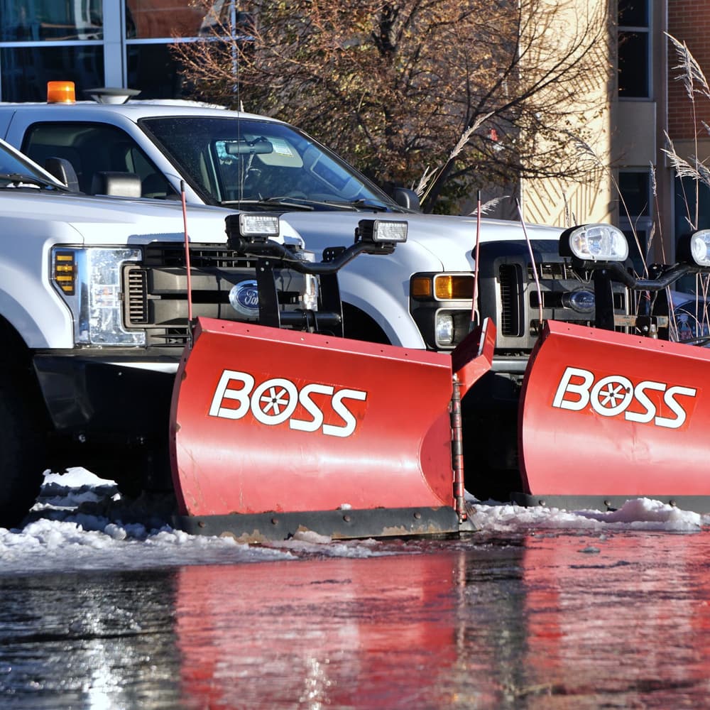 Pickup trucks fitted with heavy snow plow blades, staged for winter