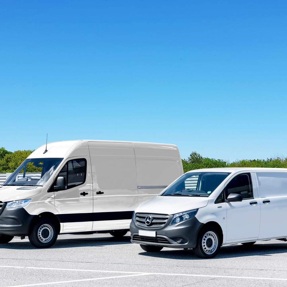 Two white work vans parked under a clear blue sky