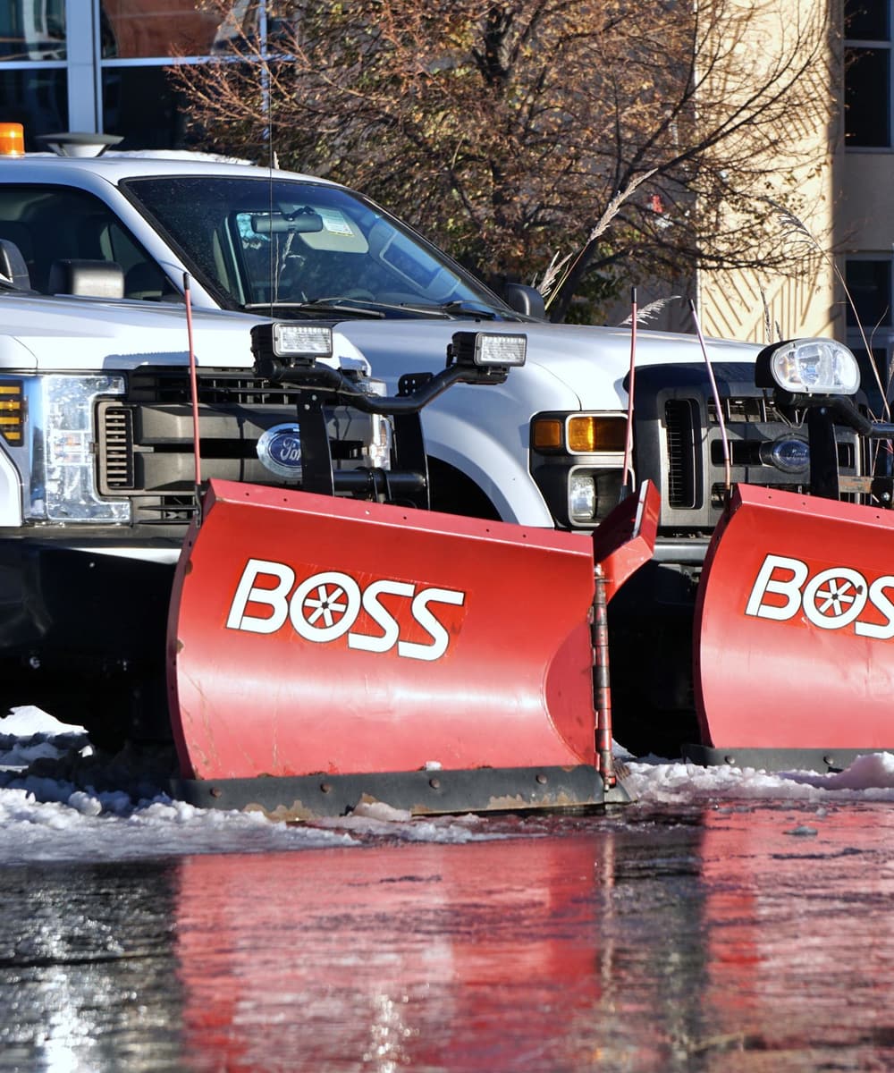 Pickup trucks fitted with heavy snow plow blades, staged for the winter season