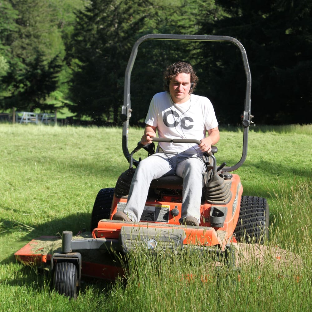 An operator cutting grass on a riding mower
